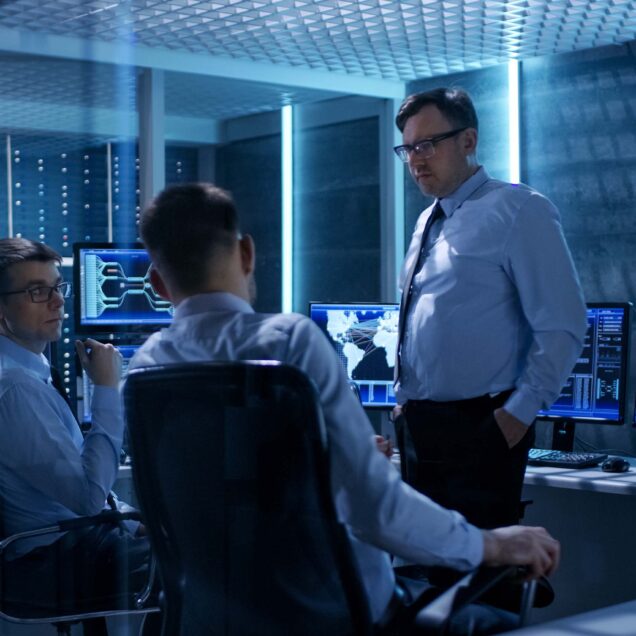 Three men working and talking in an office.