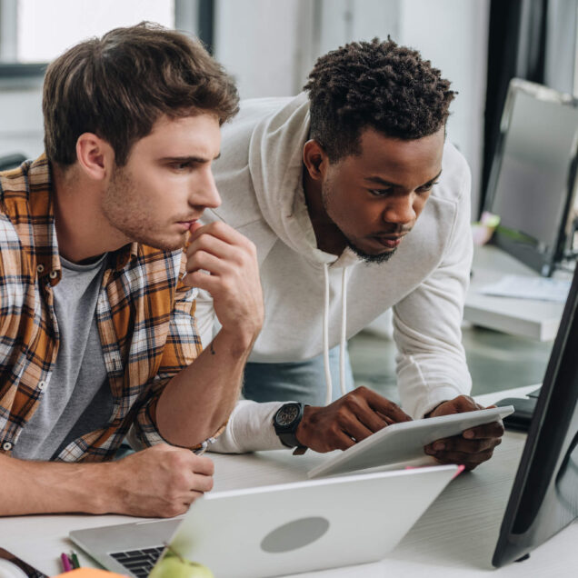 Two individuals looking at a computer together. 