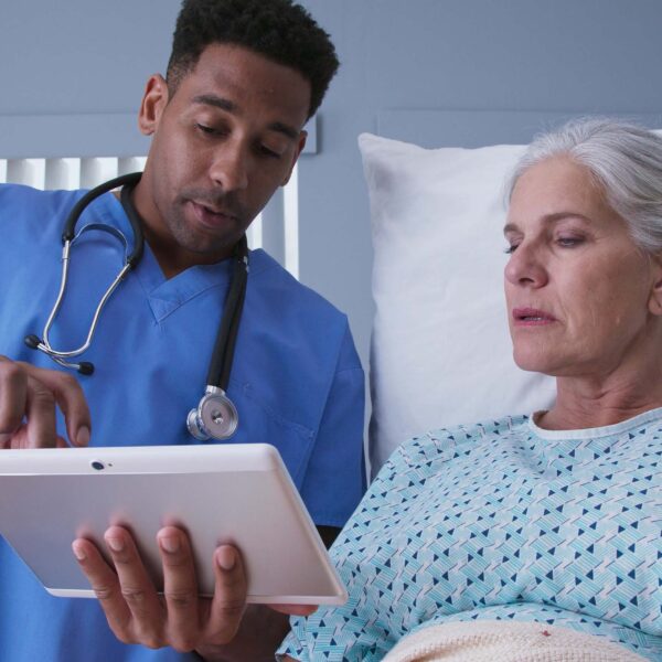 A doctor consulting a patient with both people looking at a mobile device.