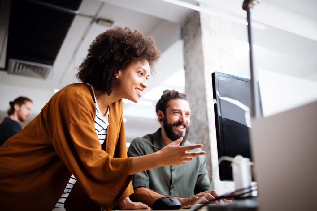 A man and woman working together and looking at a computer.