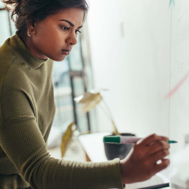 A woman writing on a whiteboard.